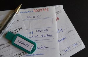 Photograph of a USB Flash Drive and a pen resting on top of a pile of checks.